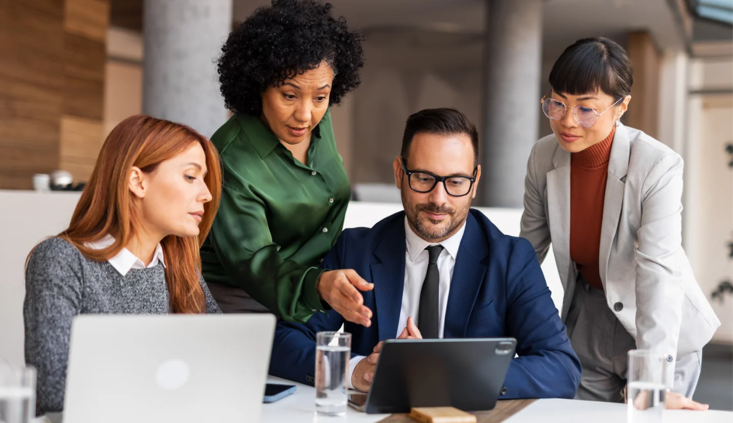 Four office workers looking at a tablet
