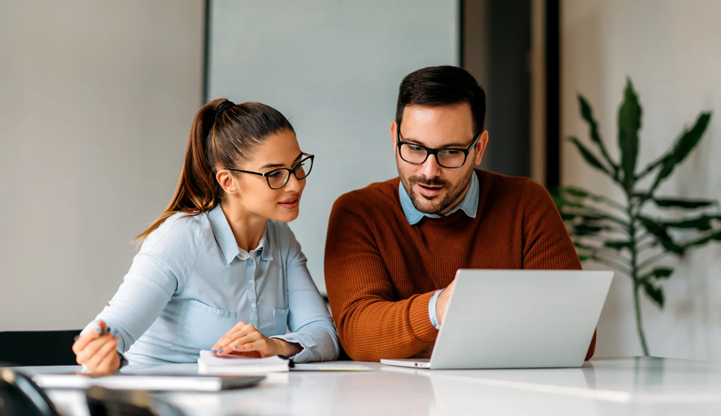 Two office workers looking at a laptop
