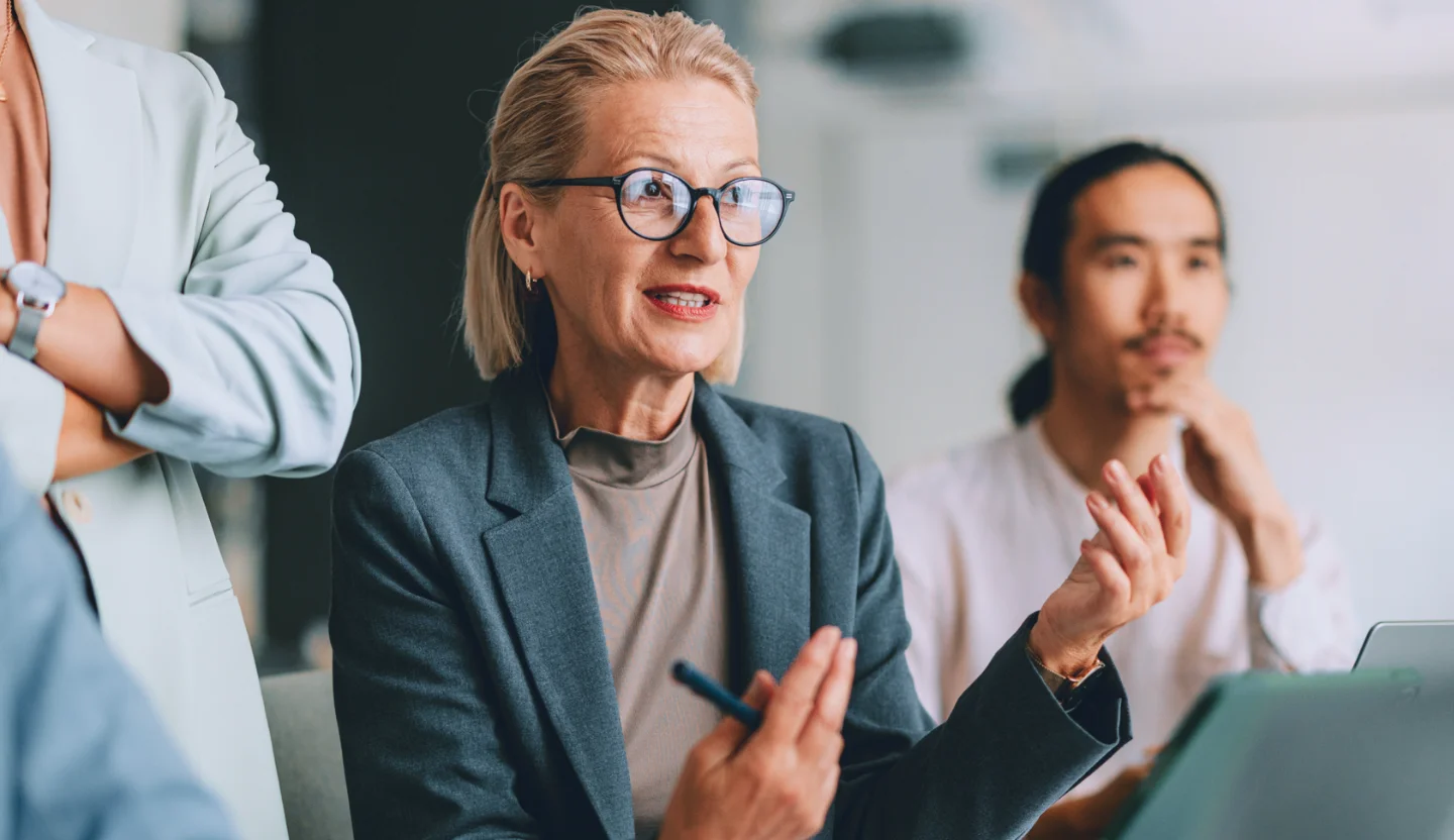 Office worker sitting at a table explaining something to colleagues