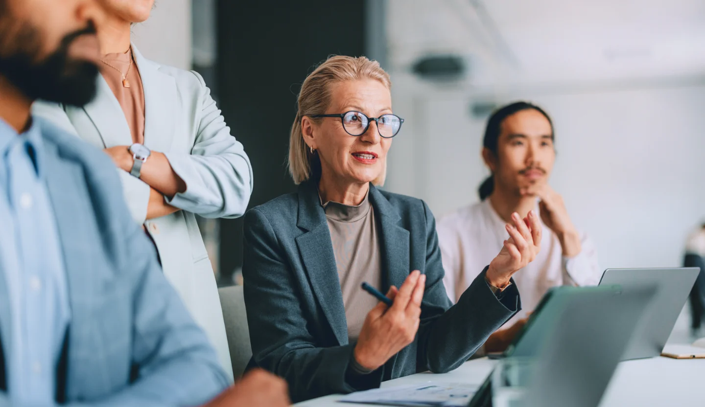 Office worker sitting at a table explaining something to colleagues