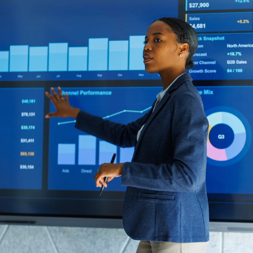 Office worker standing in front of a screen displaying graphs