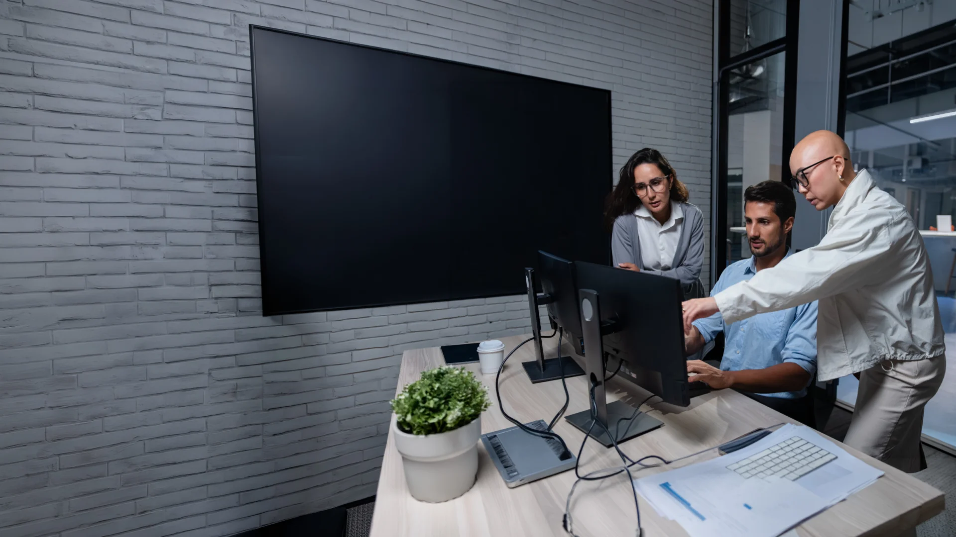 Three office workers look at a computer screen