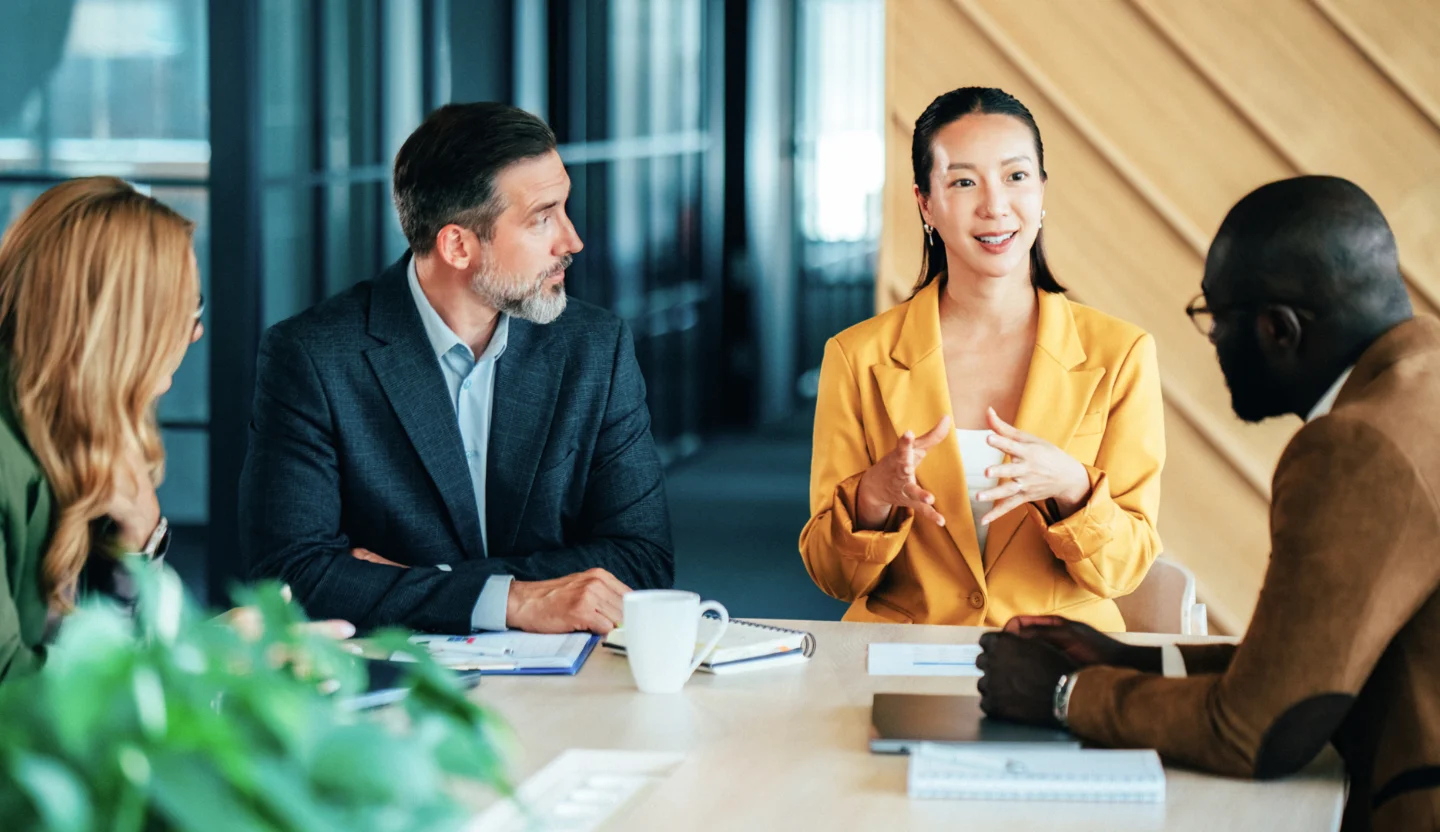 Four office workers sit around a table having a discussion