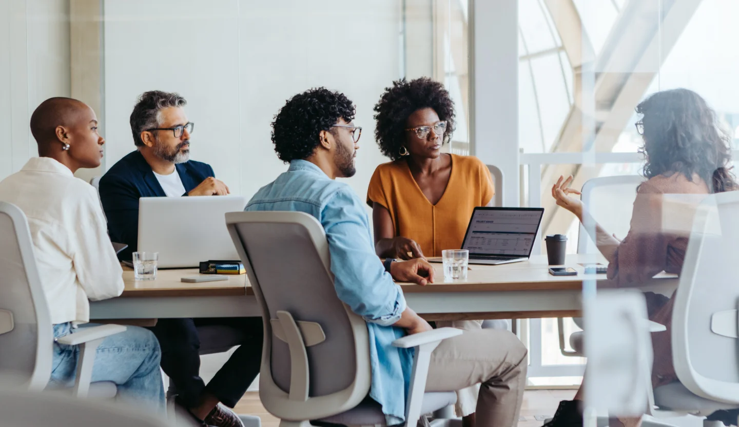 A group of office workers sit at a table and have a discussion